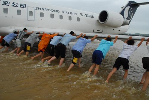 山东烟台遭遇暴雨 机场工作人员水中救飞机